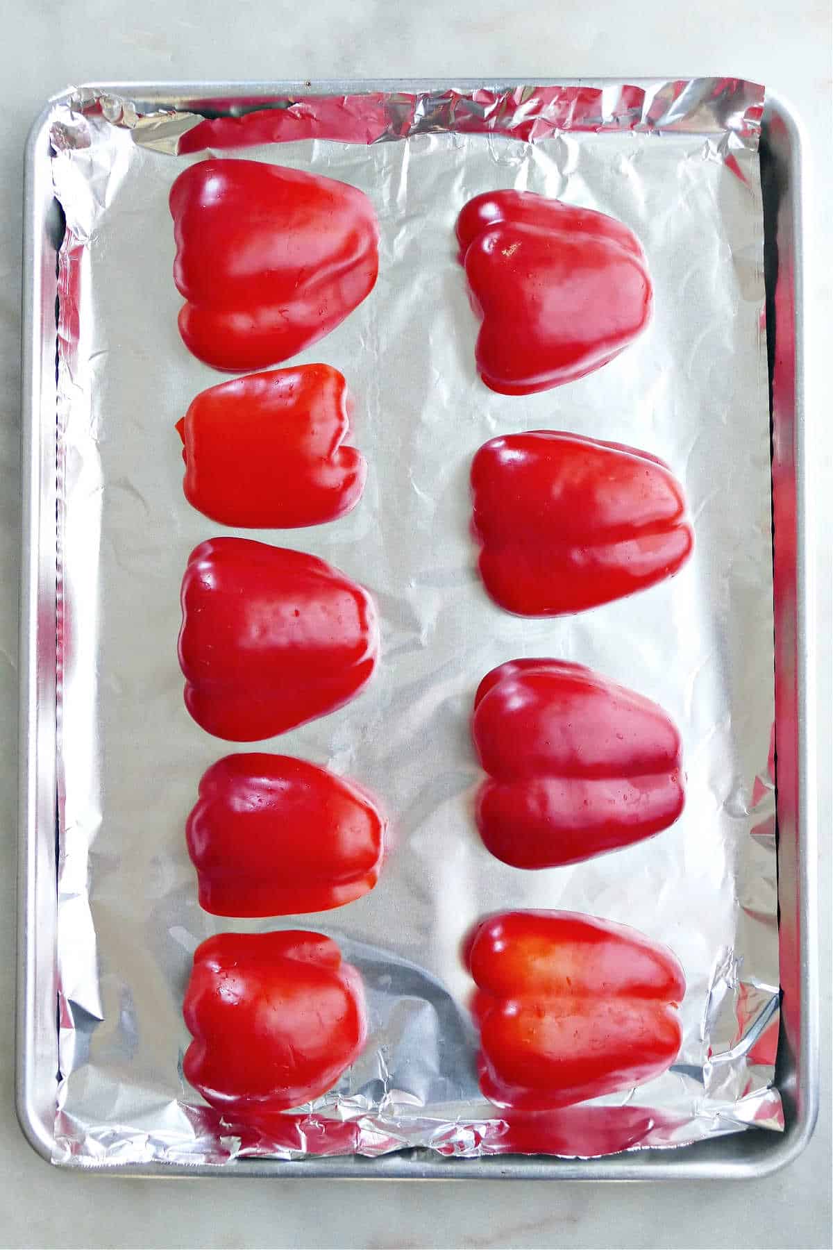 nine halves of red bell peppers on a baking sheet with foil