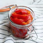 roasted red peppers on a glass jar on a striped napkin