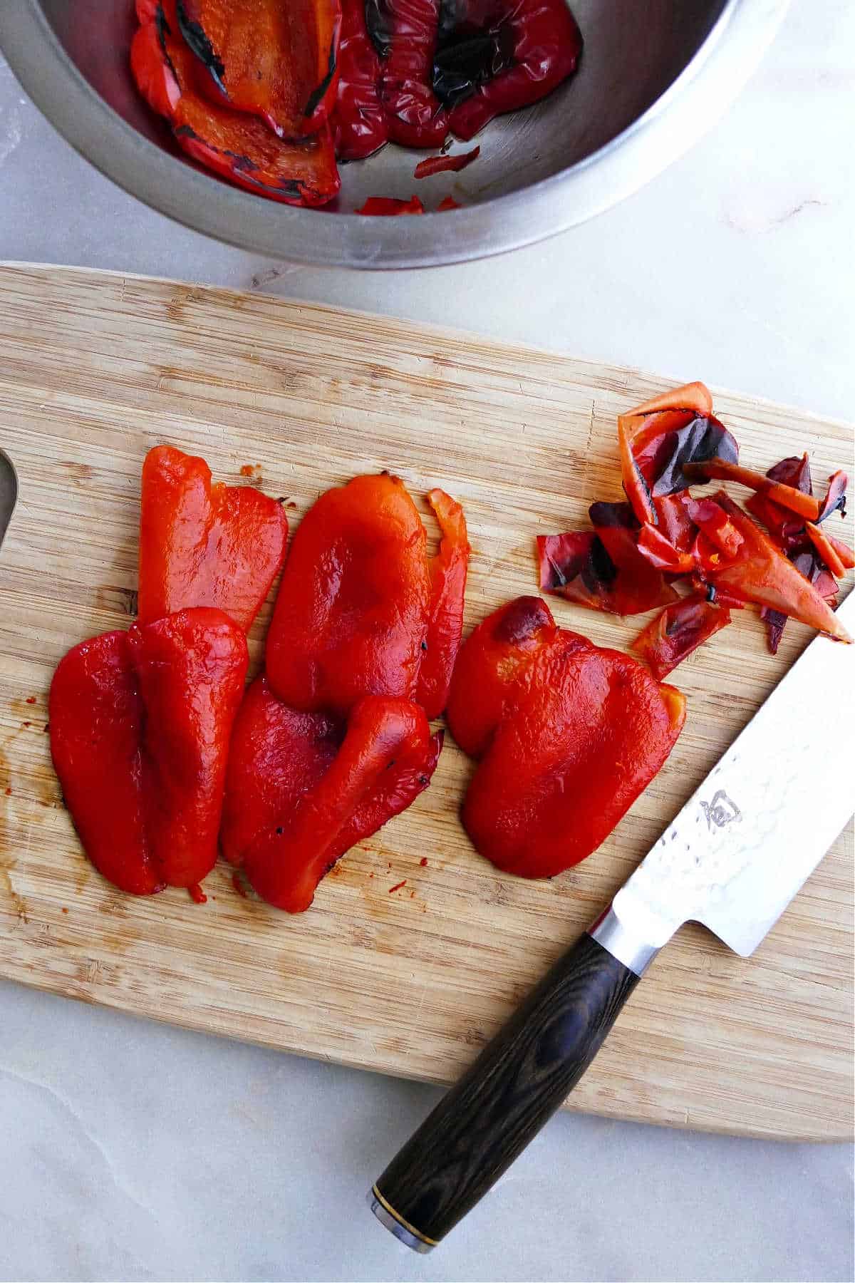 roasted red peppers with the blackened skins removed on a cutting board