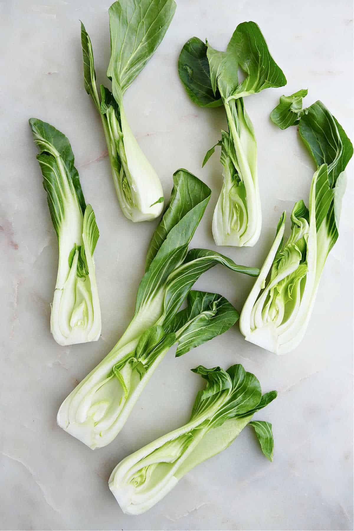 baby bok choy halves spread out next to each other on a counter
