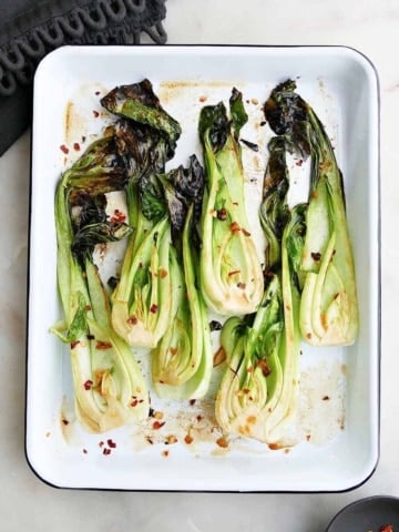 square image of roasted bok choy on a rectangular serving tray