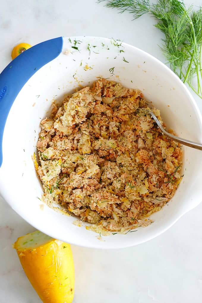 flaked salmon, squash, bread crumbs, and seasonings in a mixing bowl with a fork