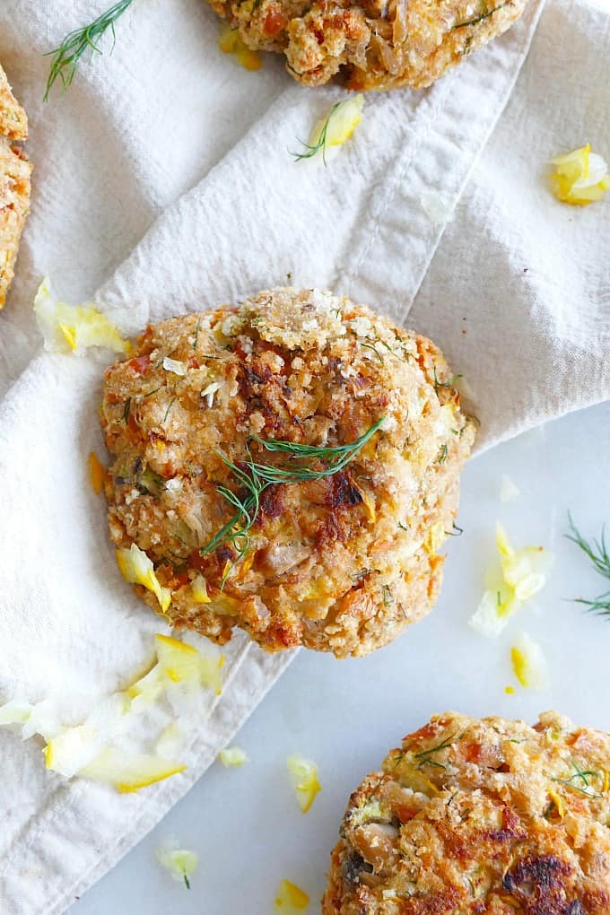 close up of a dill salmon burger on a napkin surrounded by grated squash