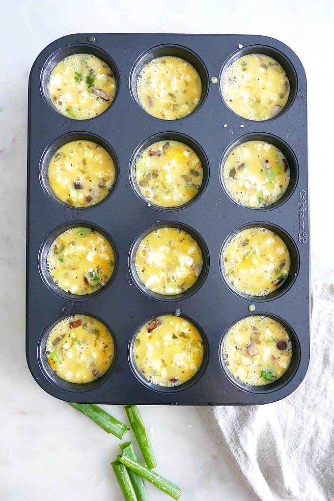 a muffin tin filled with ingredients for healthy breakfast egg muffins