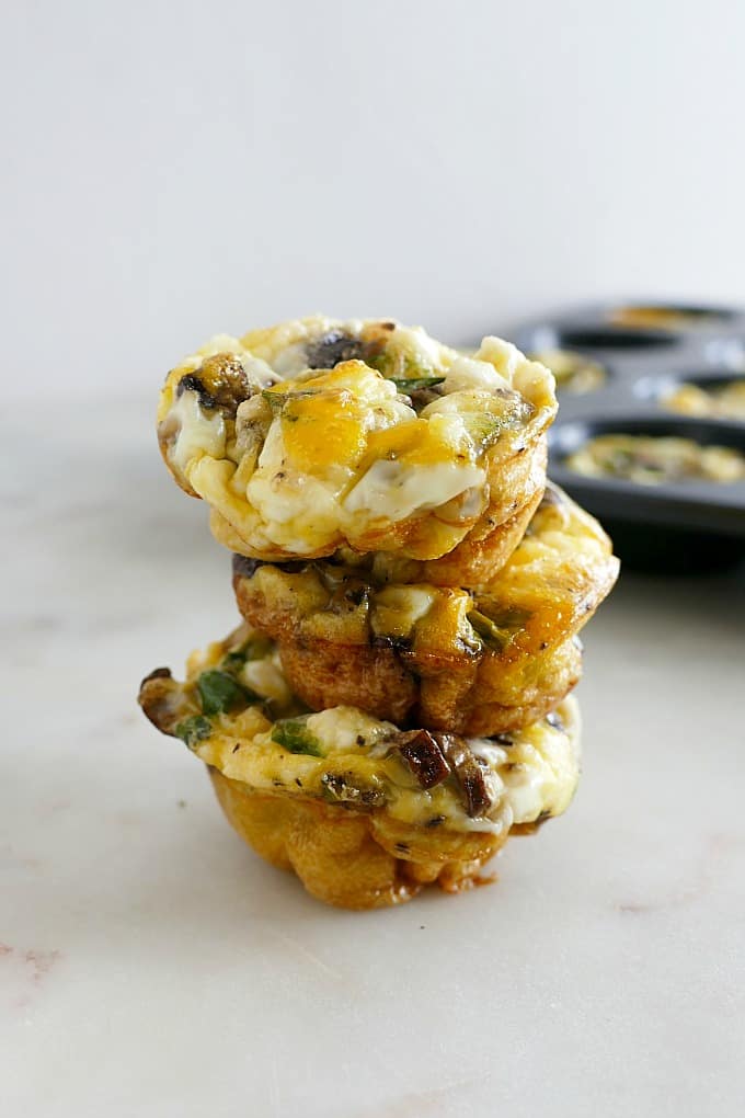 three Healthy Breakfast Egg Muffins with Mushrooms and Scallions stacked on top of each other