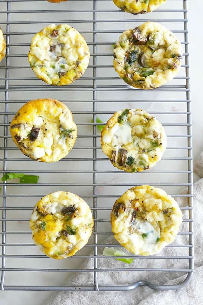 six Breakfast Egg Muffins with Mushrooms and Scallions next to each other on a cooling rack