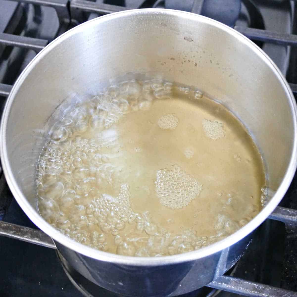 Vinegar, water, salt, and sugar simmering in a saucepan.