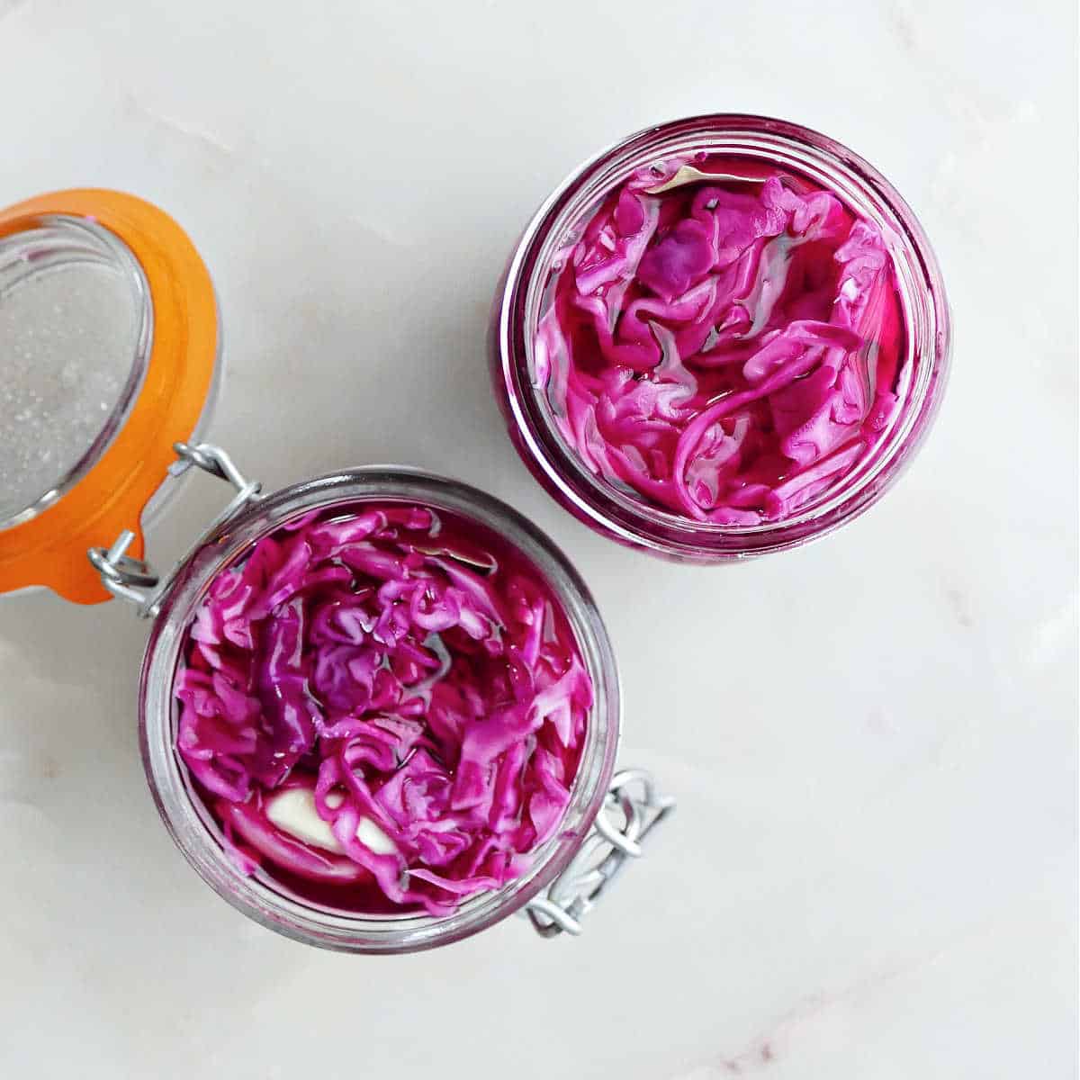 Two glass jars with pickled red cabbage after sitting for a few hours.
