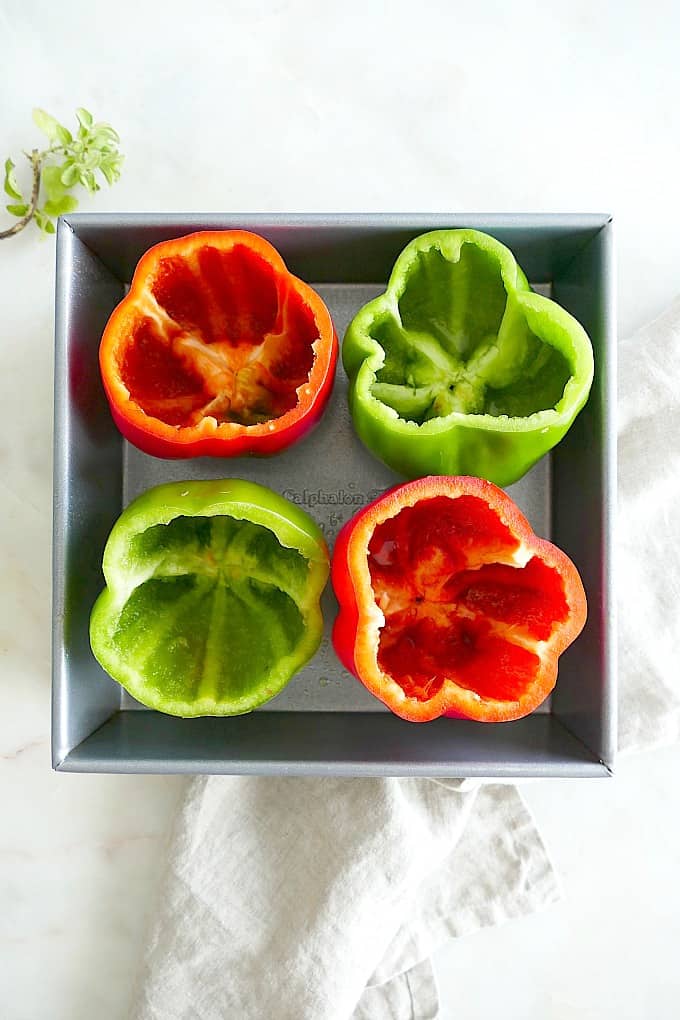 4 bell peppers with tops and seeds removed in a baking dish
