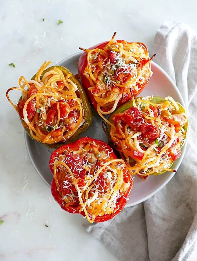 4 Spaghetti Stuffed Bell Peppers topped with cheese on a serving plate