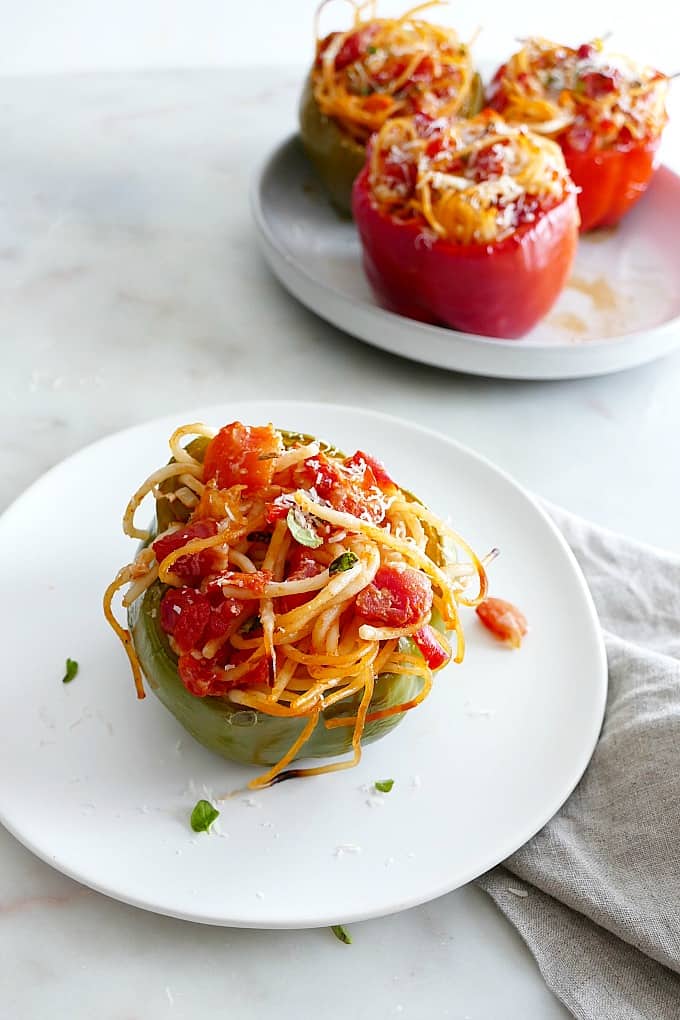 one stuffed bell pepper on a white plate in front of a platter