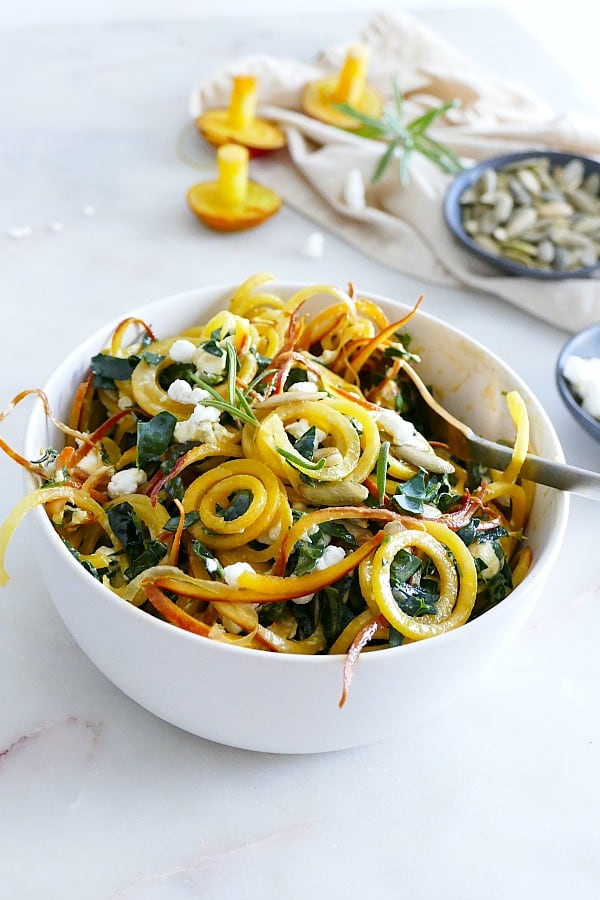 side angle of spiralized golden beet salad in a white bowl with a spoon