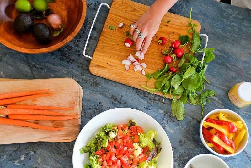 blue counter with bamboo cutting boards and white bowls of chopped vegetables