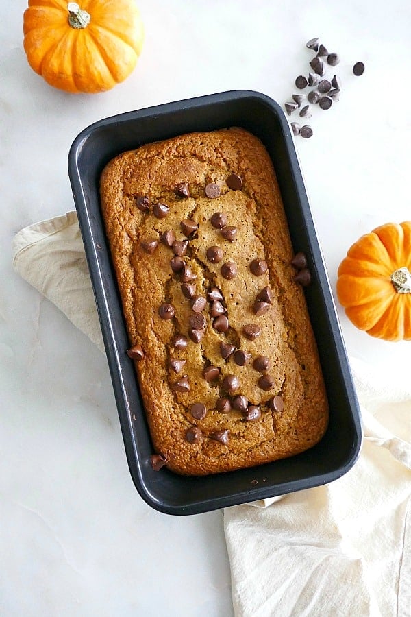 pumpkin banana oat bread topped with chocolate chips in a loaf pan on a counter
