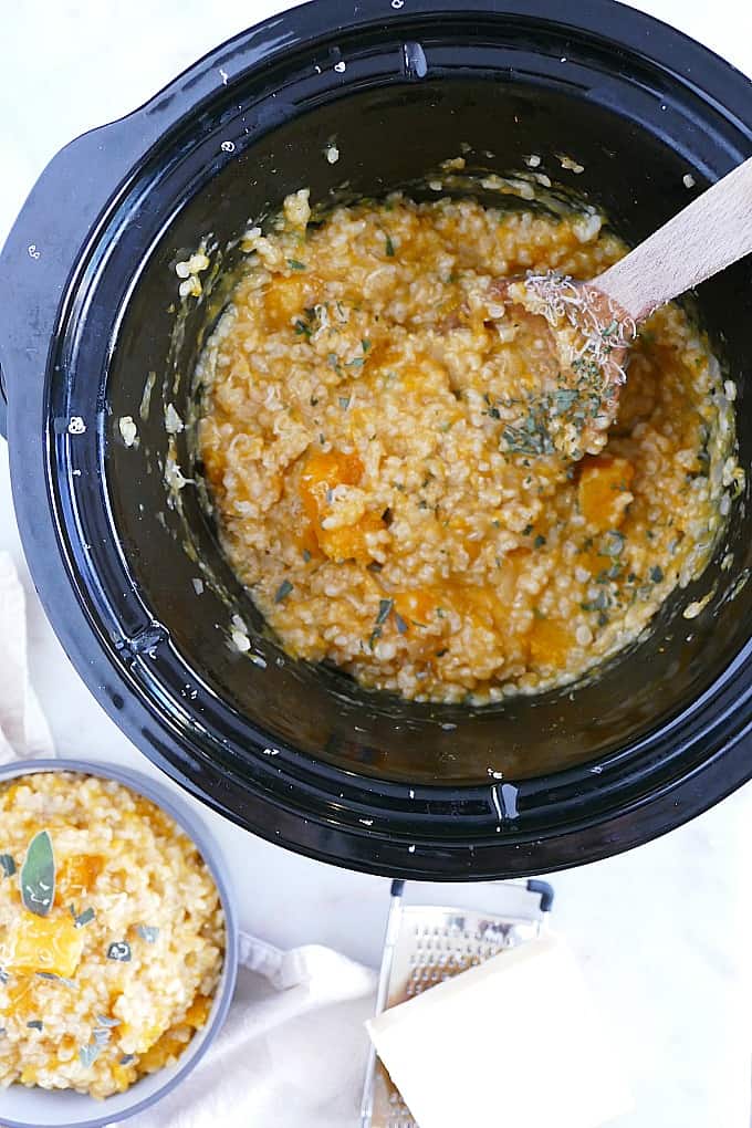 butternut squash risotto in a slow cooker with a wooden spoon
