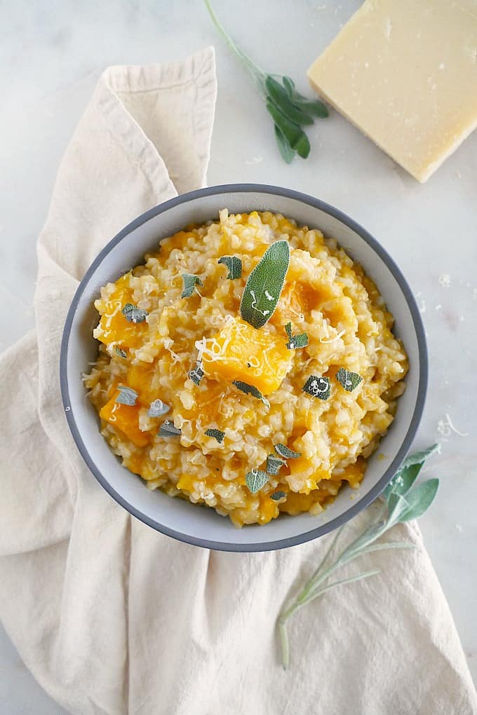 slow cooker butternut squash risotto in a gray bowl on yellow napkin with sage