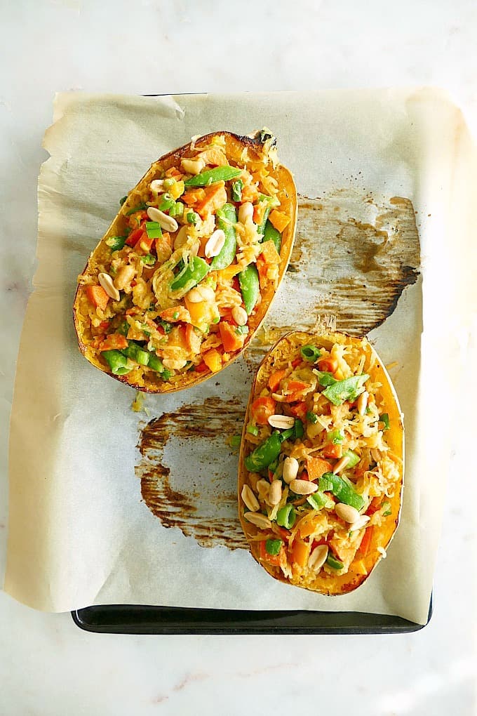 2 halves of Spaghetti Squash Pad Thai on parchment paper on a baking sheet