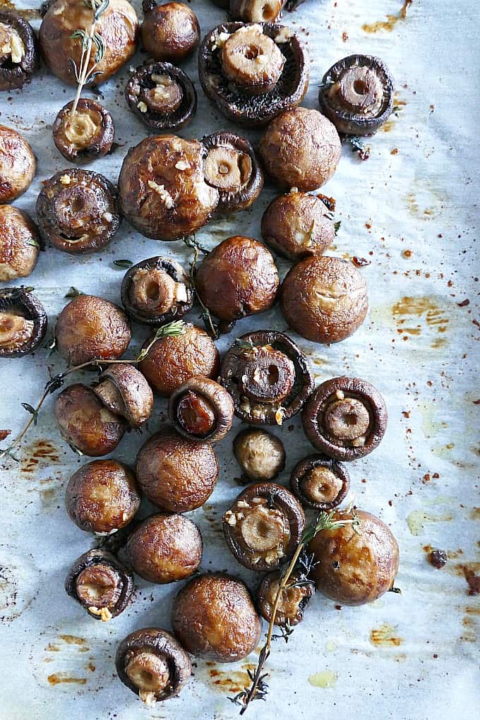 Garlic Thyme Roasted Mushrooms spread out on a piece of parchment paper on a baking sheet