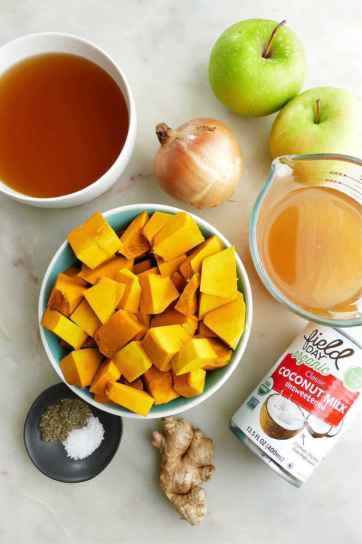 Kabocha Squash, Granny smith apples, ginger, and onion spread out on a counter