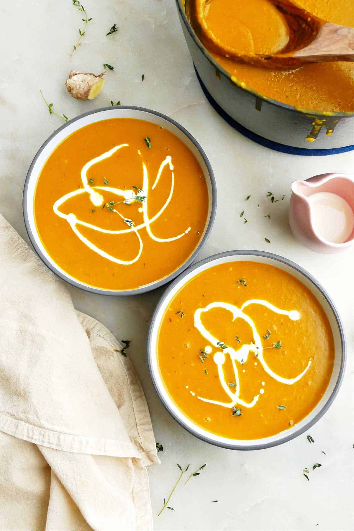 bowl of orange Kabocha Squash Soup topped with pumpkin seeds and fresh thyme