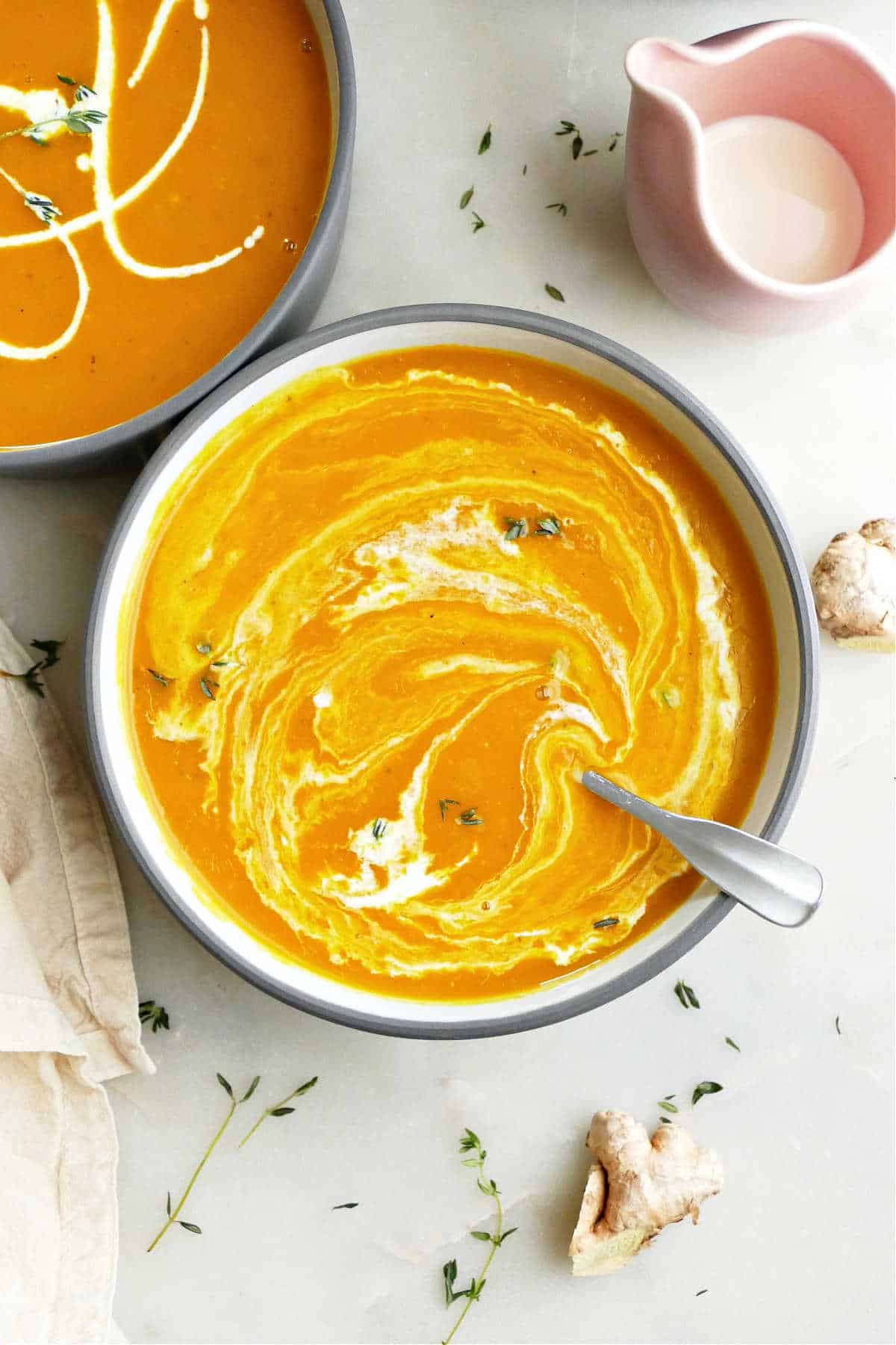 bowl of kabocha squash soup topped with pumpkin seeds and thyme on a counter