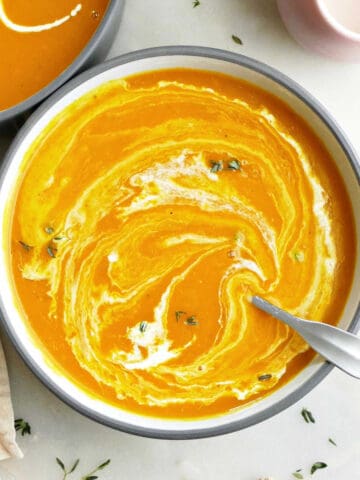 Kabocha Squash Soup in a bowl with coconut milk and thyme