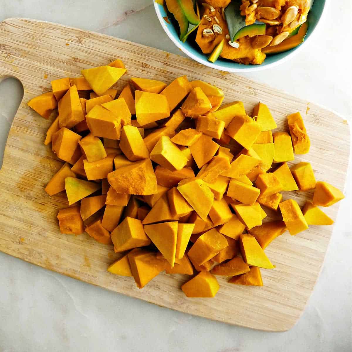kabocha squash diced into cubes on a cutting board on a counter
