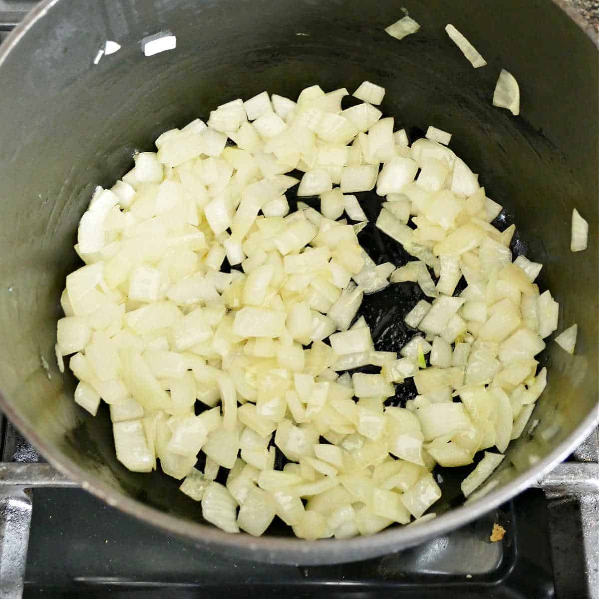 diced onion cooking in olive oil in a soup pot over a stove