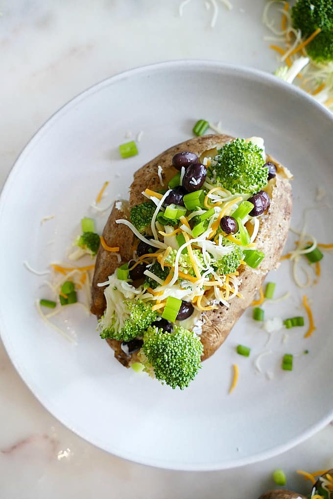 Healthy Baked Potato topped with broccoli, beans, and cheese on a plate