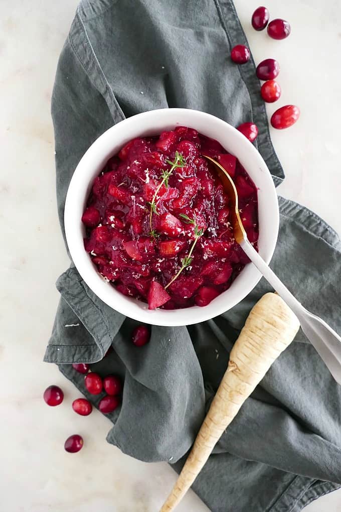 cranberry sauce with parsnips in a white bowl with a gold spoon on a blue napkin