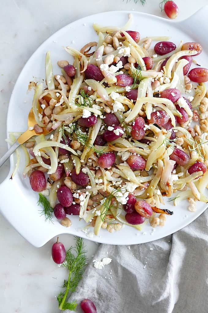 warm fennel salad with grapes, feta, and beans on a circular white plate
