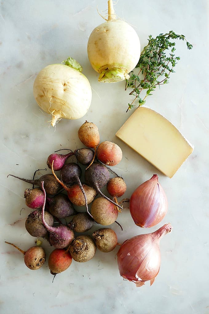 2 turnips, a bunch of beets, thyme, gruyere, and shallots on a countertop