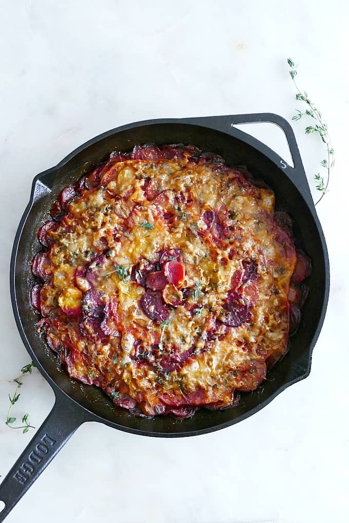 a colorful Turnip and Beet Gratin with melted cheese in a black cast iron skillet