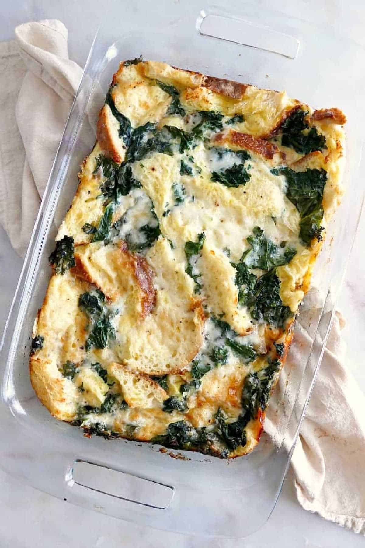 Sourdough Breakfast Strata with Kale in a glass pyrex on a yellow napkin