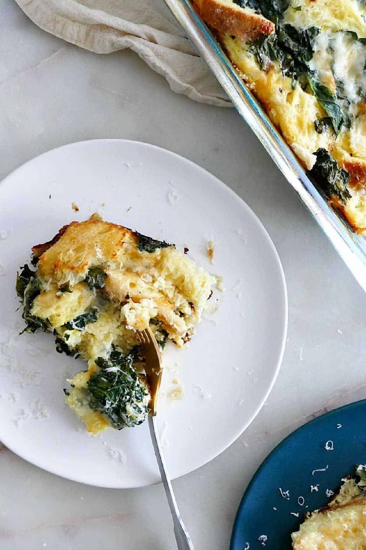 a slice of Sourdough Breakfast Strata with Kale on a white plate next to the dish