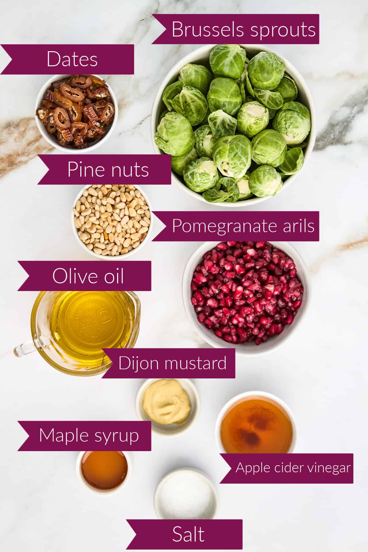 Sliced dates, Brussels sprouts pine nuts, pomegranate arils, oil, mustard, syrup, vinegar, and salt with labels.