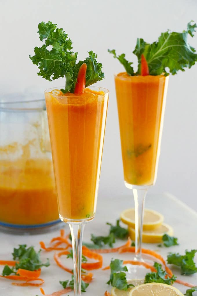 two champagne flutes with fresh carrot and orange juice mixed with prosecco