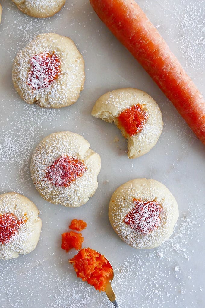 a handful of thumbprint cookies with carrot jam including one with a bite