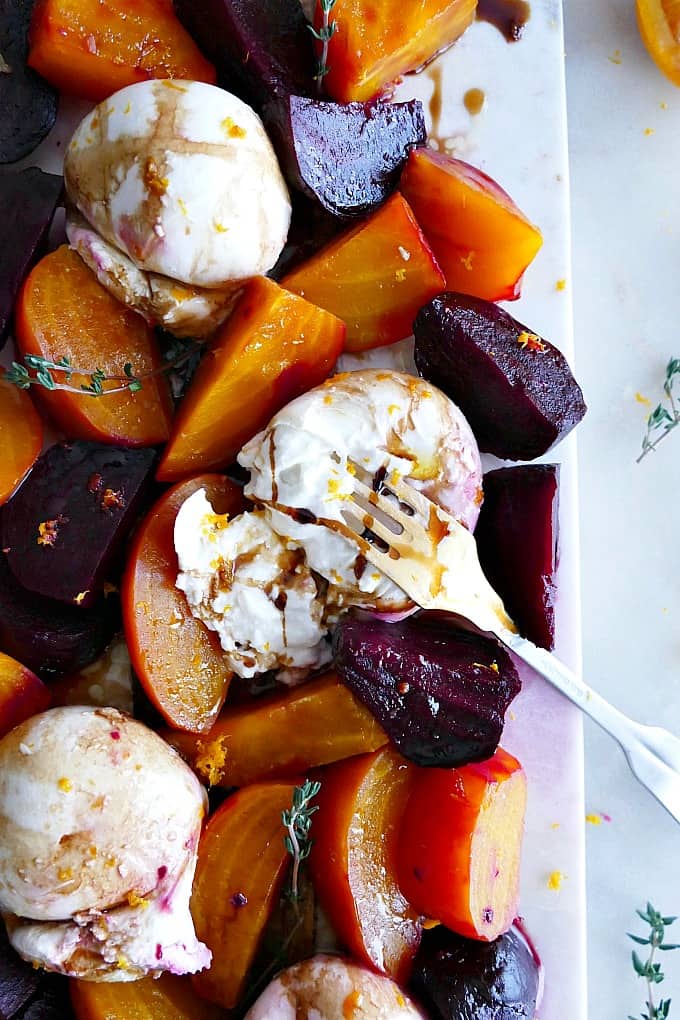 close up of a burrata cheese ball with a fork surrounded by roasted beets