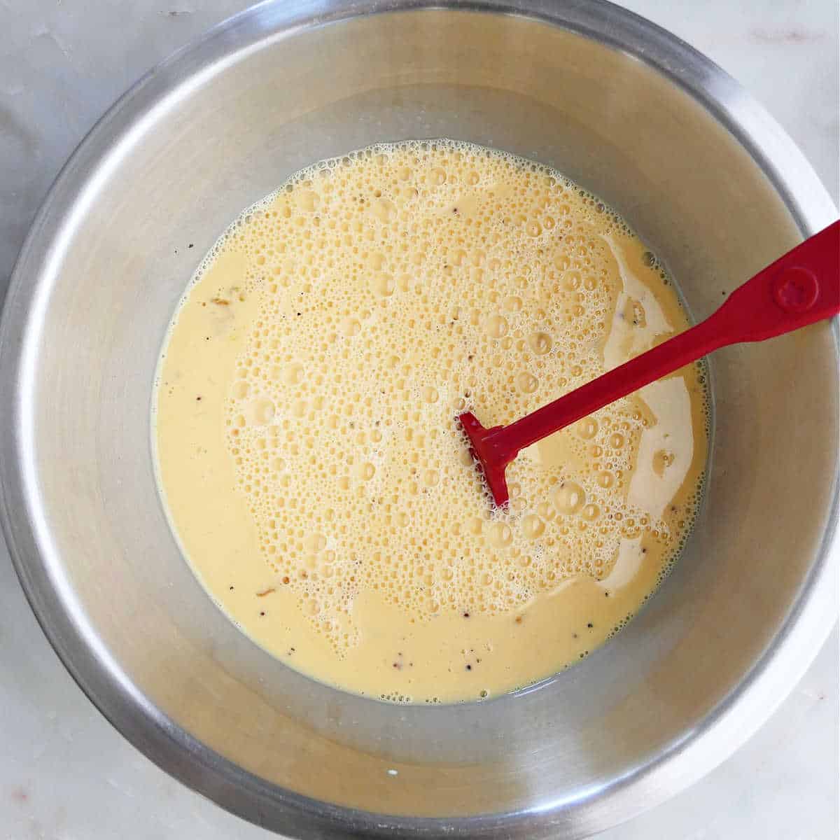 whisked eggs with milk, mustard, salt, and pepper in a mixing bowl
