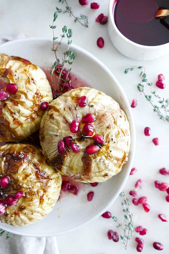 close up of one Whole Roasted Kohlrabi with pomegranate seeds on a white plate