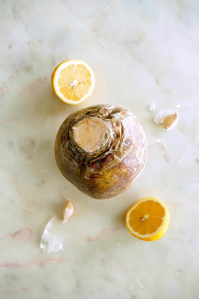 a rutabaga in between two lemon halves and garlic cloves on a white counter