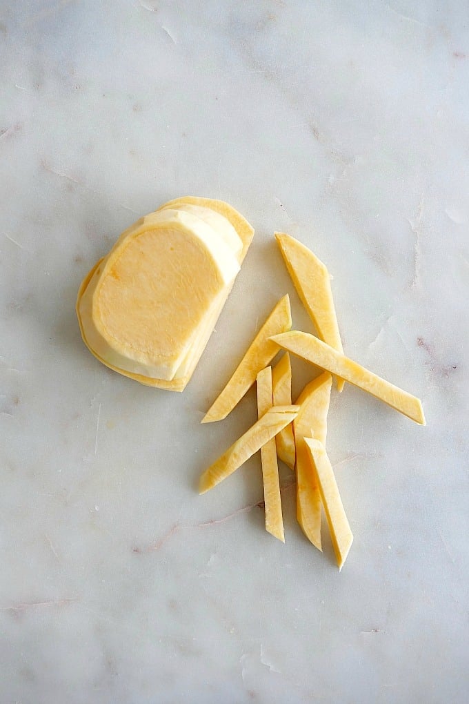 rutabaga slices on top of each other and cut into fries on a counter