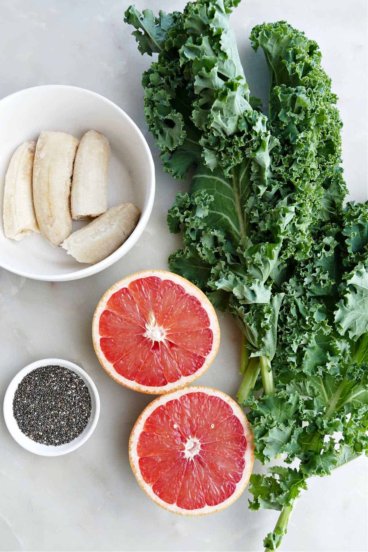 banana, kale leaves, grapefruit, and chia seeds on a counter