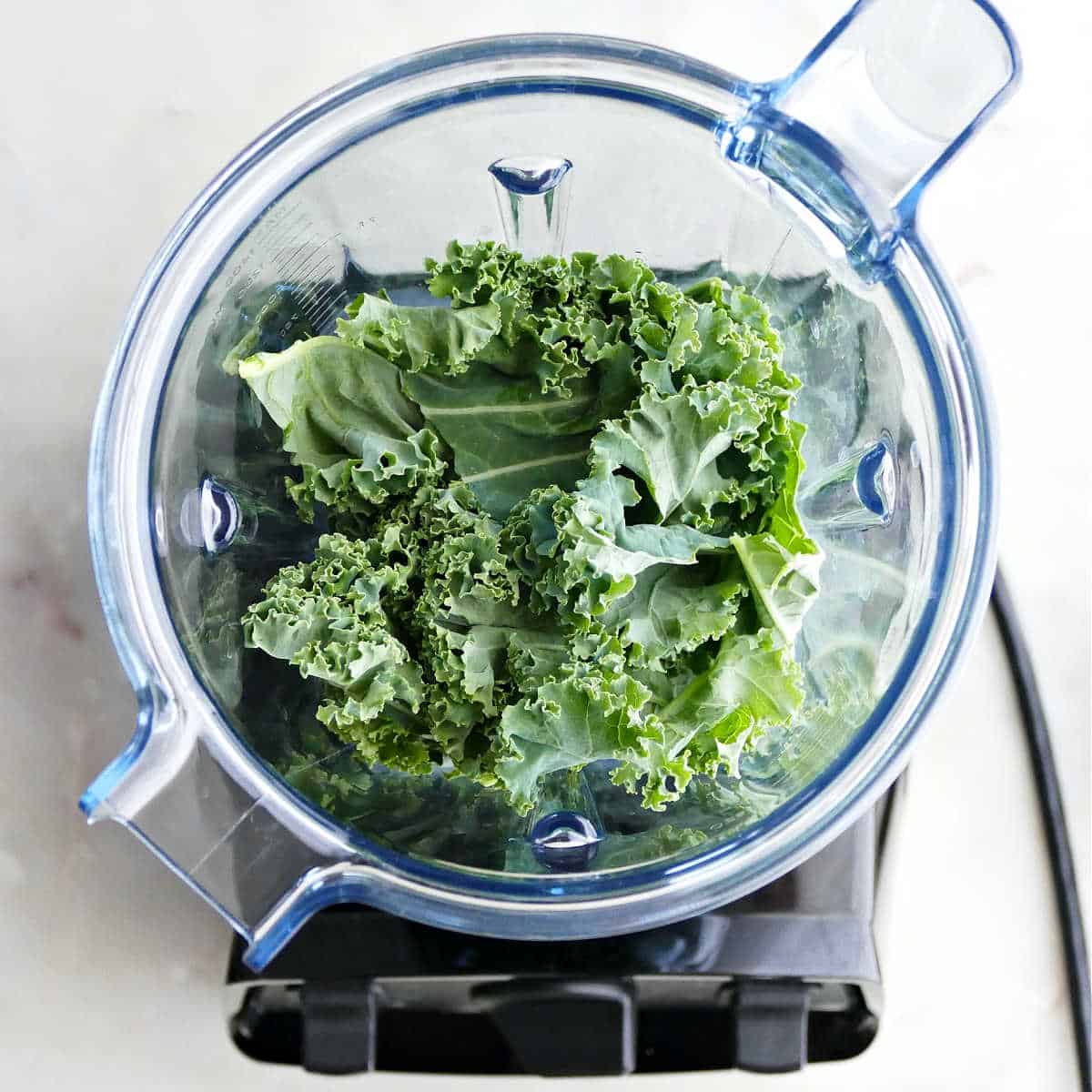 torn kale leaves in a blender on a counter