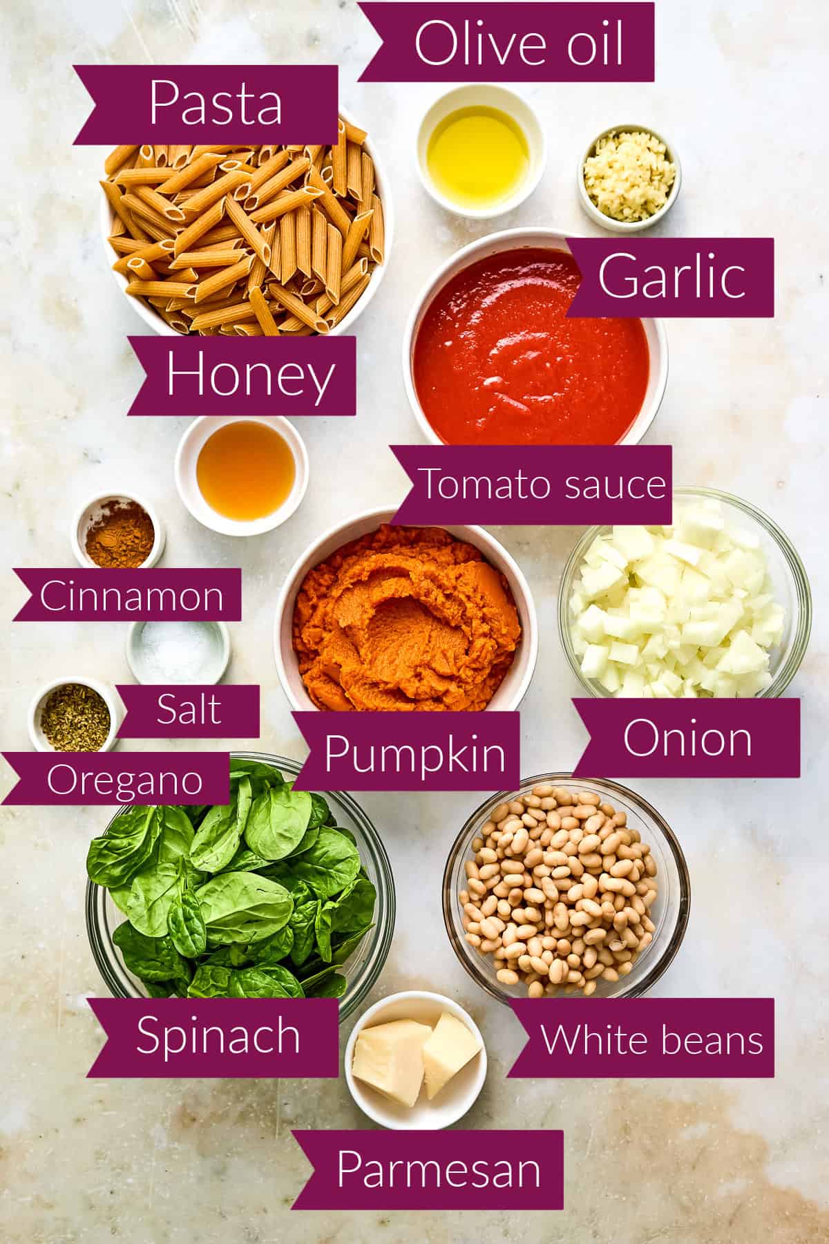 Pasta, oil, garlic, tomato sauce, honey, spices, pumpkin, onion, spinach, beans, and cheese with labels.
