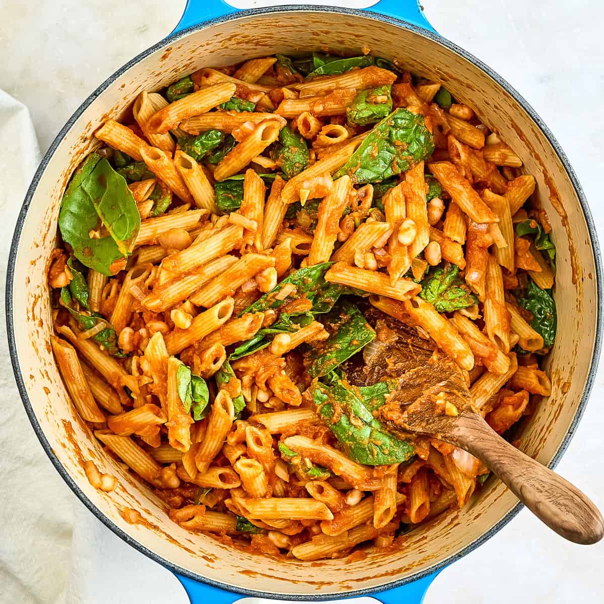 Pumpkin pasta with spinach and beans in a large pot.
