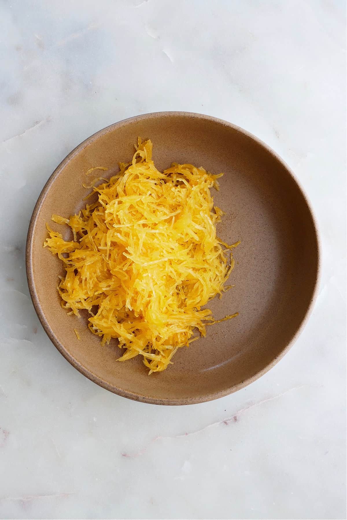 spaghetti squash noodles in a brown serving bowl on a counter