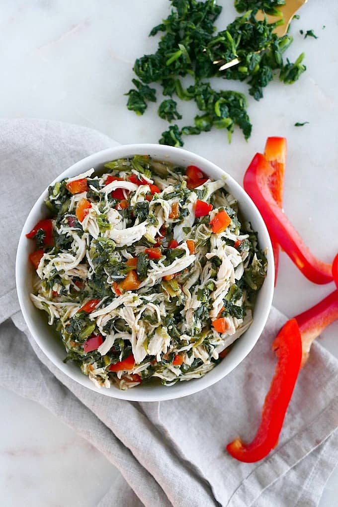 Slow Cooker Mexican shredded Chicken with spinach and bell peppers in a white bowl