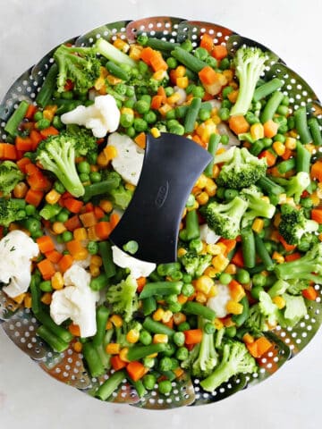 mixed vegetables in a vegetable steamer basket on a counter